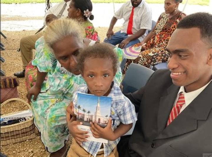 A child holds the printed program for the Port Vila Vanuatu Temple groundbreaking ceremony.