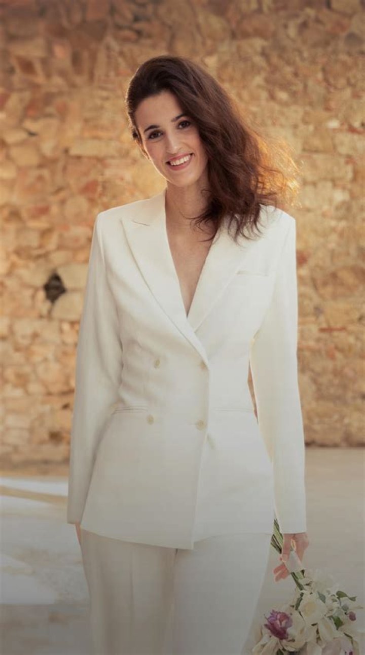 bride wearing ivory suit poses with groom