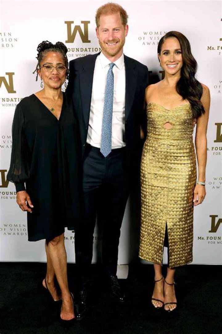 Meghan Markle smiles in a white high collar top